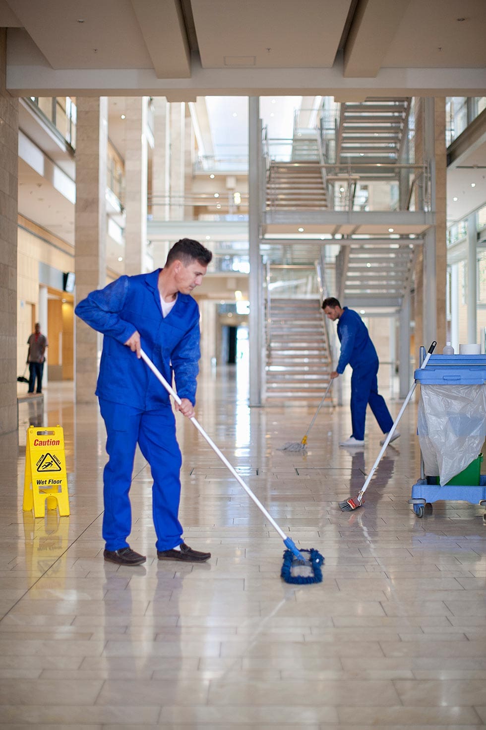 Male cleaners mopping in office atrium